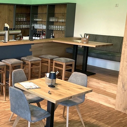 Maßgefertigter Gastraum mit Gastrotheke, Tischen, Stühlen und Bank aus der Schreinerei Hofmann Kreuzwertheim für Natur & City Camping Ellwangen.