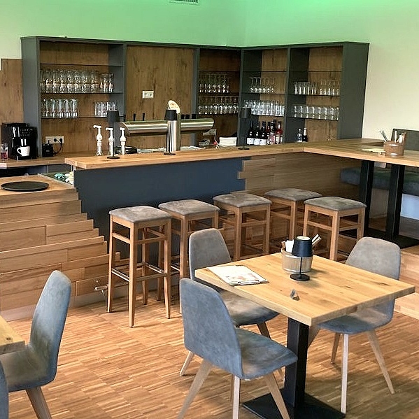 Maßgefertigter Gastraum mit Gastrotheke, Tischen, Stühlen und Bank aus der Schreinerei Hofmann Kreuzwertheim für Natur & City Camping Ellwangen.