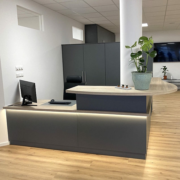 Moderne Empfangstheke aus Schichtstoff in Anthrazit mit abgerundetem Thekenbrett – maßgefertigte Praxismöbel und Ladenbau von Hofmann, auch für Gastro Möbel geeignet.